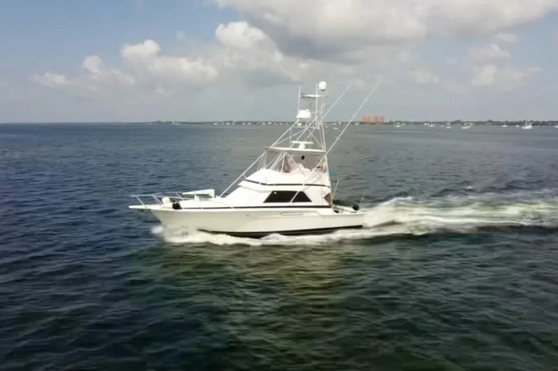  Yacht Photos Pics 1988 Bertram 43 Flybridge cruising on open water under a partly cloudy sky.