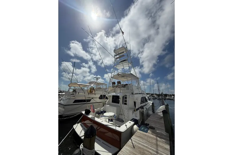  Yacht Photos Pics 1988 Bertram 43 Flybridge yacht docked under a sunny sky with scattered clouds.