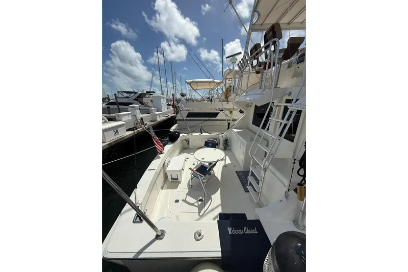  Yacht Photos Pics 1988 Bertram 43 Flybridge yacht docked, featuring spacious deck and seating under a sunny sky.