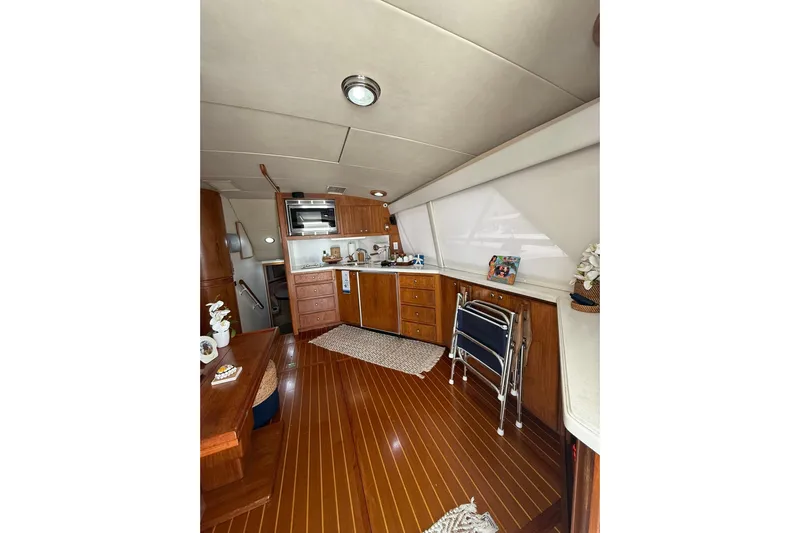  Yacht Photos Pics Interior of 1988 Bertram 43 Flybridge yacht with wooden flooring and compact kitchen area.