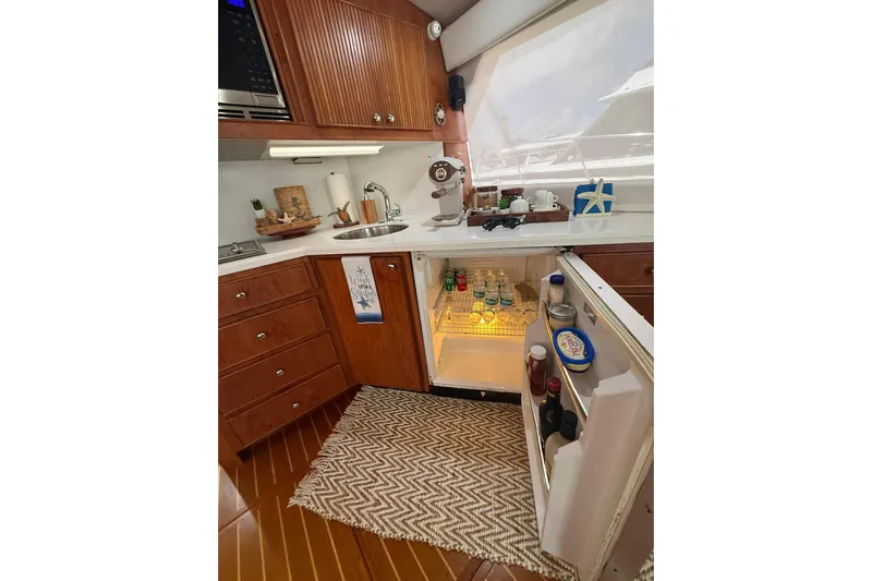 Yacht Photos Pics 1988 Bertram 43 Flybridge kitchen with open fridge, wooden cabinets, and countertop accessories.