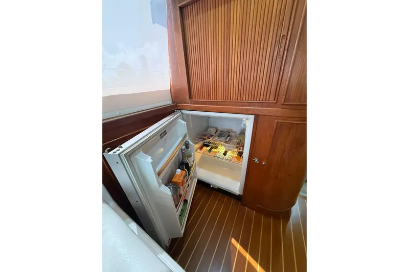  Yacht Photos Pics Open fridge in 1988 Bertram 43 Flybridge yacht, showcasing stocked interior and wooden cabinetry.