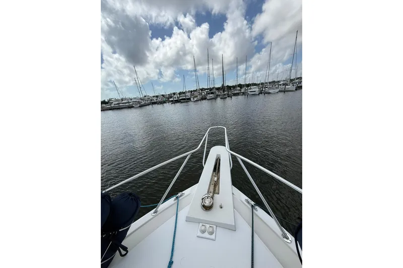  Yacht Photos Pics Bow view of 1988 Bertram 43 Flybridge in a marina under cloudy skies.