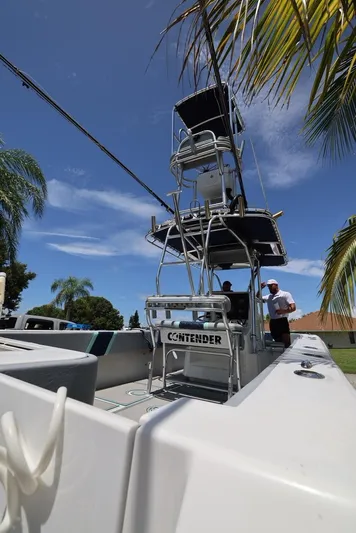 Late Fees Yacht Photos Pics 2001 Contender 27 Open boat under palm trees with clear blue sky.