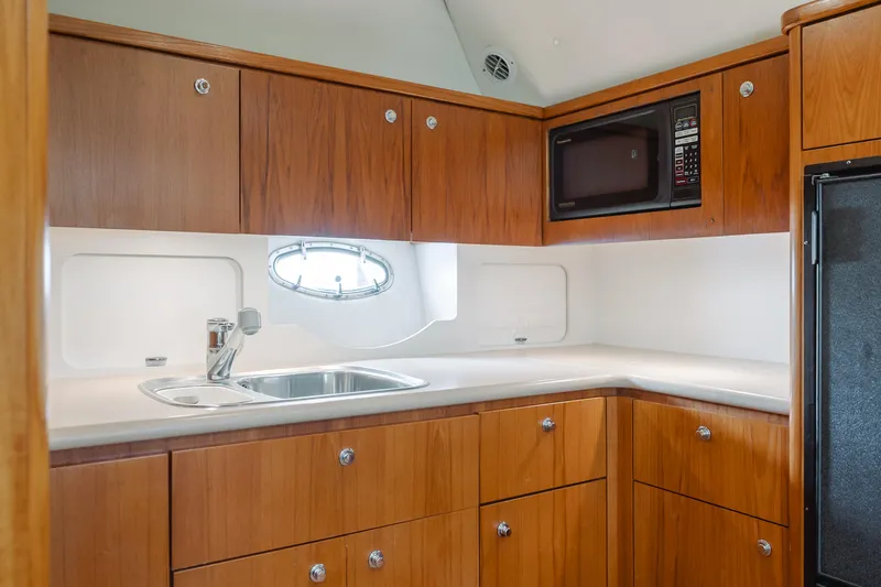 Half Dozen Yacht Photos Pics 2001 Tiara Yachts 4100 Open kitchen with wood cabinets, sink, and microwave.