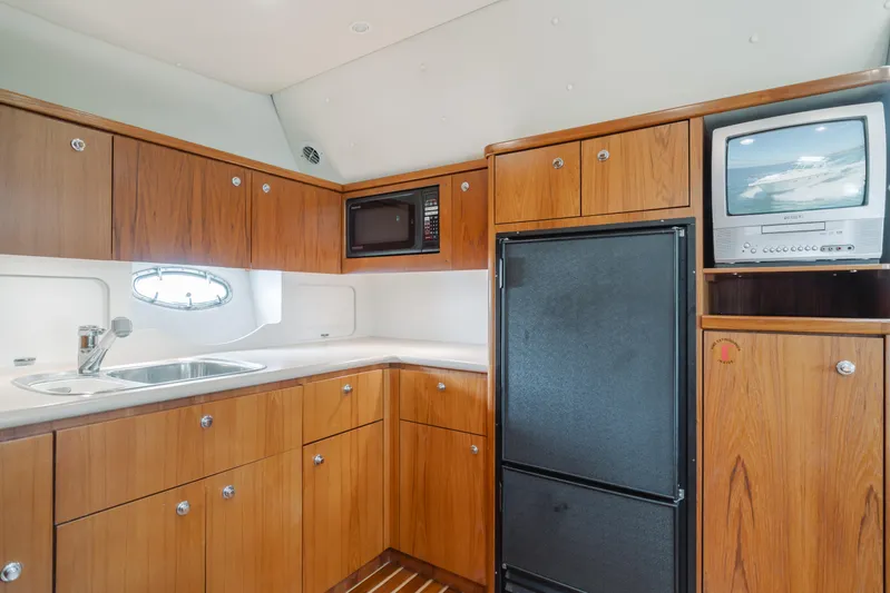 Half Dozen Yacht Photos Pics 2001 Tiara Yachts 4100 Open kitchen with wood cabinets, sink, fridge, and TV.