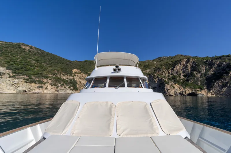  Yacht Photos Pics Moonen 85 yacht from 1989 cruising near rocky coastline under clear blue sky.