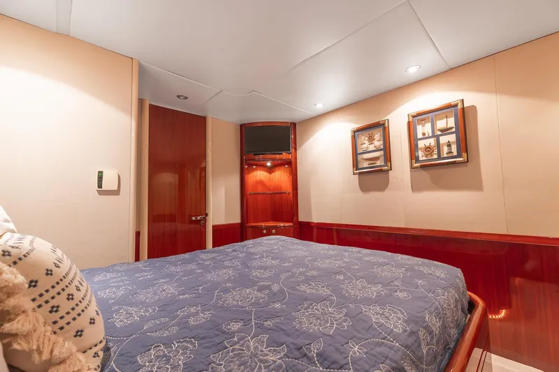 Fomo2 Yacht Photos Pics Luxurious bedroom interior of 2002 Lazzara 80 Skylounge yacht with elegant decor and cozy bedding.