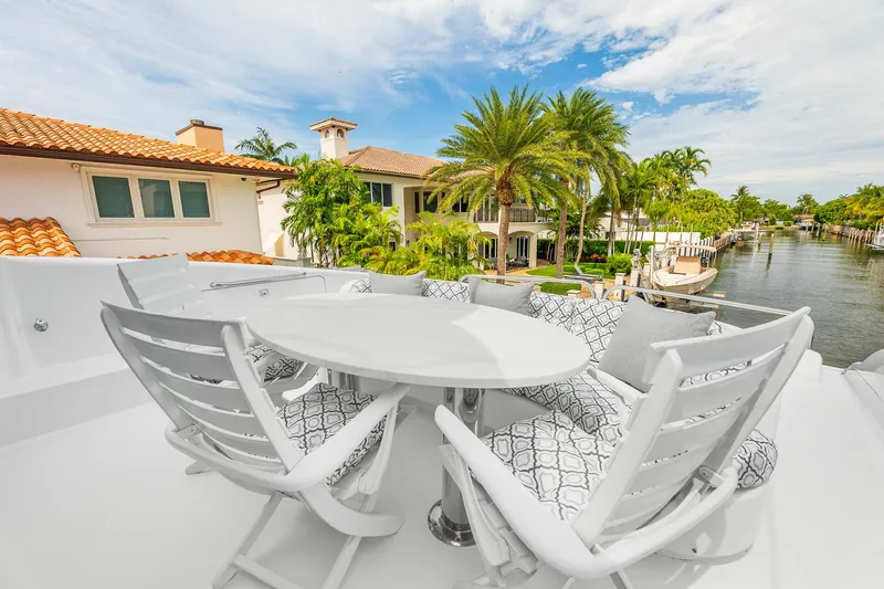 Fomo2 Yacht Photos Pics Luxury yacht deck with white seating, table, and waterfront view; Lazzara 80 Skylounge, 2002.