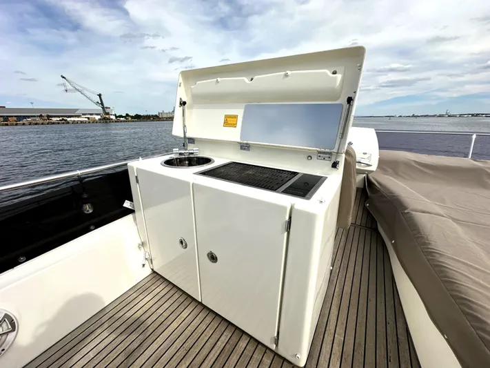  Yacht Photos Pics Outdoor kitchenette on 2013 Prestige 500 yacht with sink and grill, docked by the water.