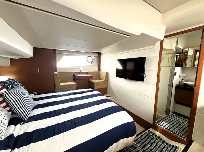  Yacht Photos Pics Luxurious 2013 Prestige 500 yacht bedroom with striped bedding, seating area, TV, and ensuite bathroom.