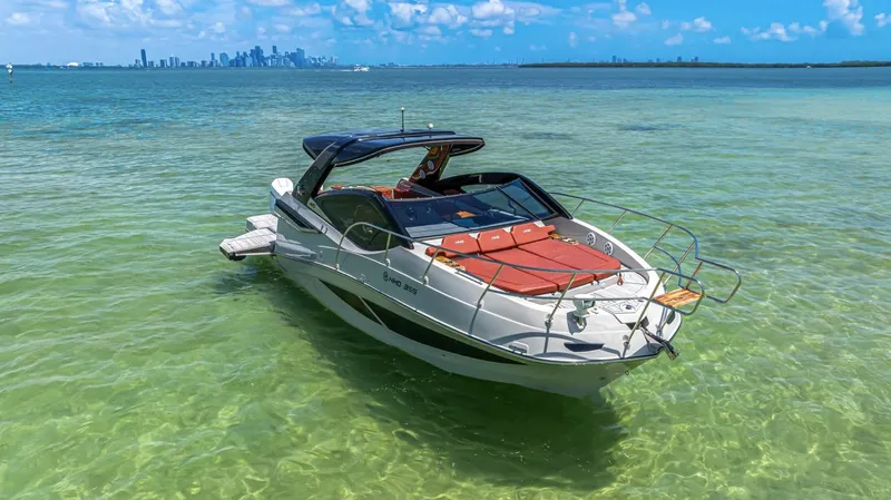  Yacht Photos Pics 2024 NHD 355 Open Deck boat on clear turquoise water, city skyline in background.