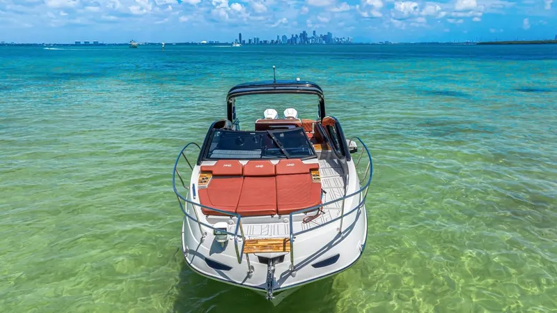  Yacht Photos Pics 2024 NHD 355 Open Deck boat on clear turquoise water with city skyline in background.