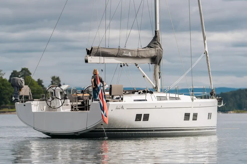  Yacht Photos Pics 2019 Hanse 548 yacht sailing on calm waters with a person on deck.