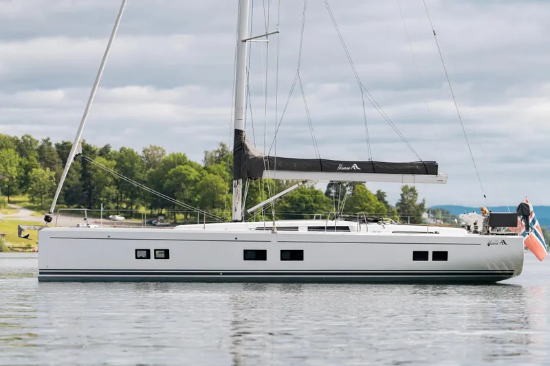  Yacht Photos Pics 2019 Hanse 548 sailboat on calm water with lush green shoreline.