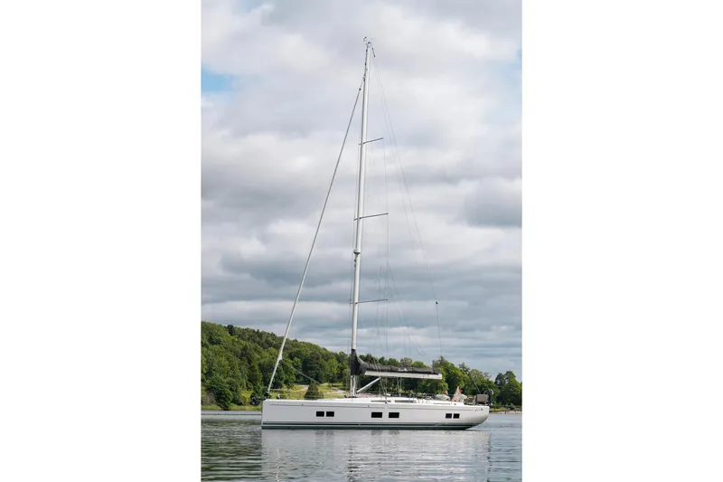 Yacht Photos Pics 2019 Hanse 548 sailboat on calm water with lush green shoreline.