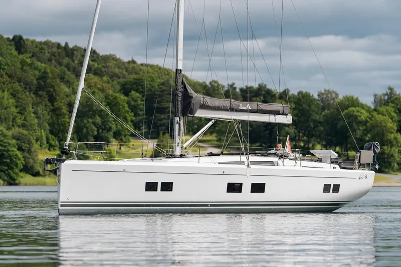  Yacht Photos Pics 2019 Hanse 548 sailboat on calm water with lush green forest background.