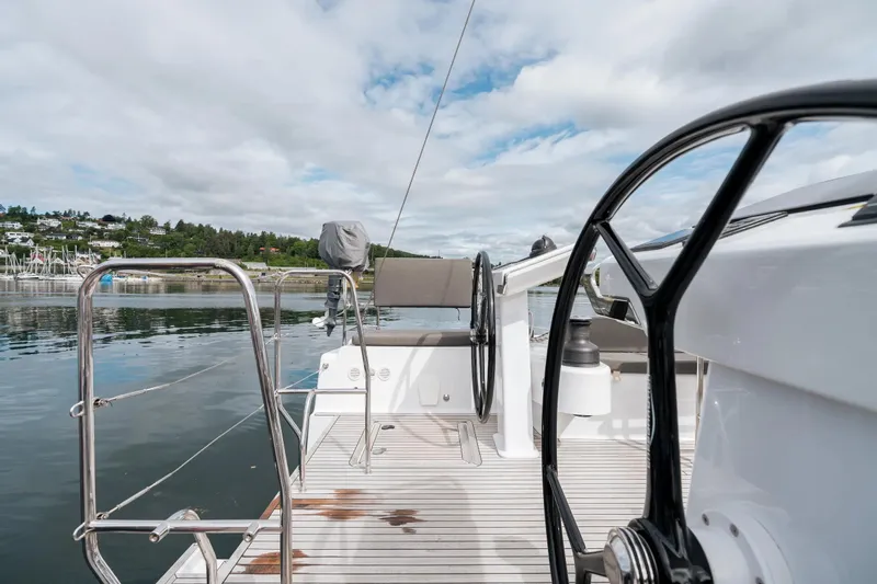  Yacht Photos Pics 2019 Hanse 548 yacht deck with dual steering wheels, docked by a scenic shoreline.