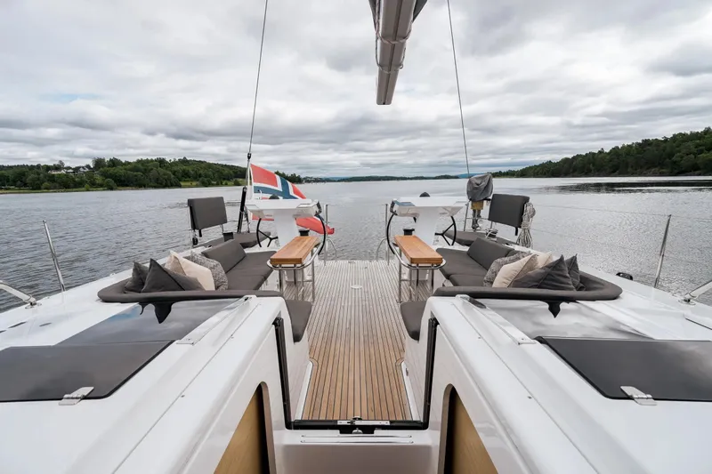  Yacht Photos Pics 2019 Hanse 548 yacht deck with seating, tables, and scenic water view.