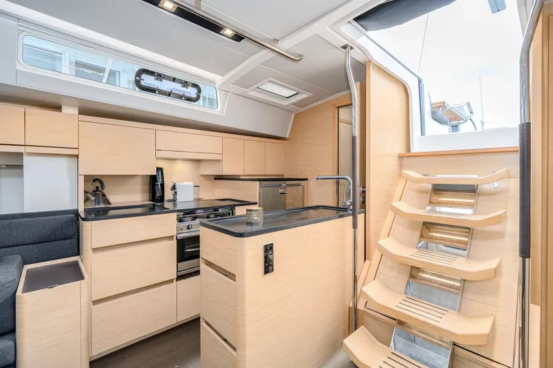  Yacht Photos Pics Modern interior of 2019 Hanse 548 yacht with sleek kitchen and wooden stairs.