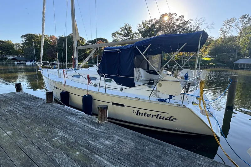 Interlude Yacht Photos Pics 2002 Beneteau Oceanis 393 sailboat docked, named "Interlude," with blue canopy and serene water backdrop.
