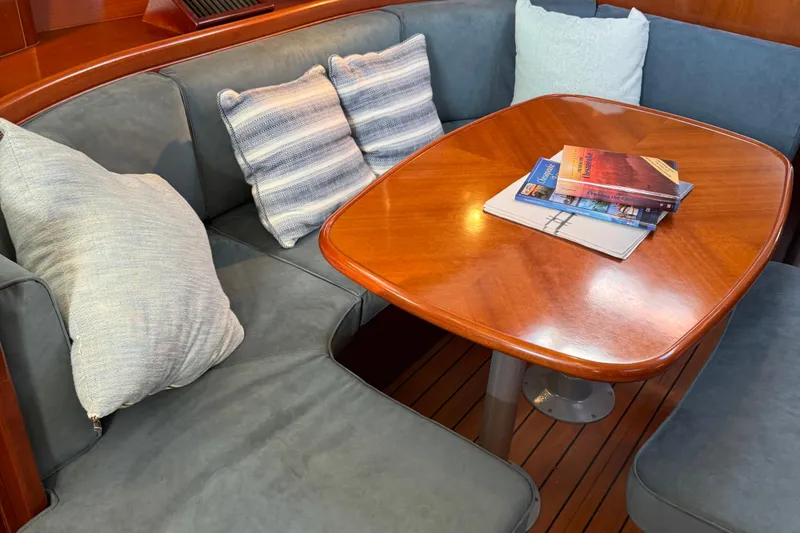 Interlude Yacht Photos Pics Cozy interior of 2002 Beneteau Oceanis 393 with cushioned seating and wooden table.