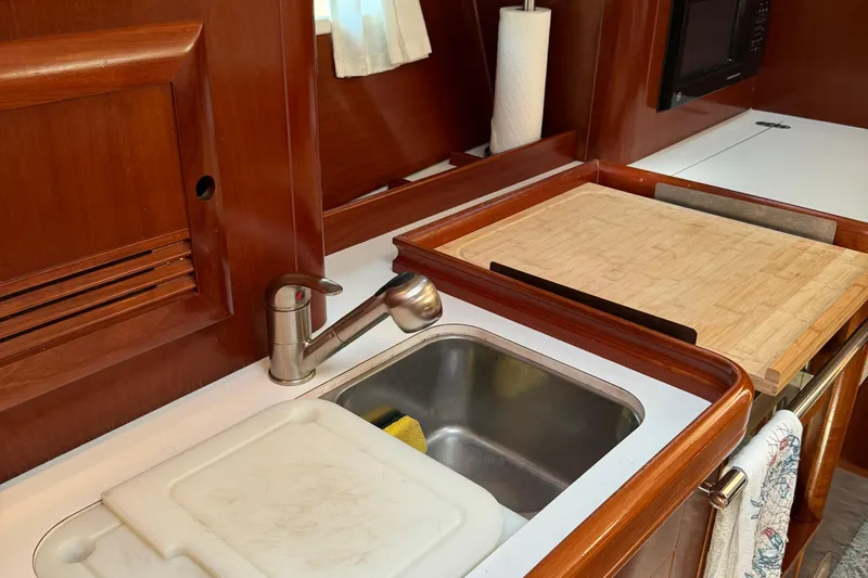 Interlude Yacht Photos Pics Galley kitchen in 2002 Beneteau Oceanis 393 sailboat with sink and cutting board.