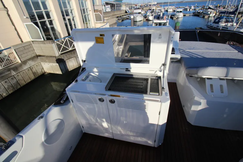  Yacht Photos Pics Outdoor kitchen on 2024 Prestige 520 yacht, featuring grill and sink, docked at marina.