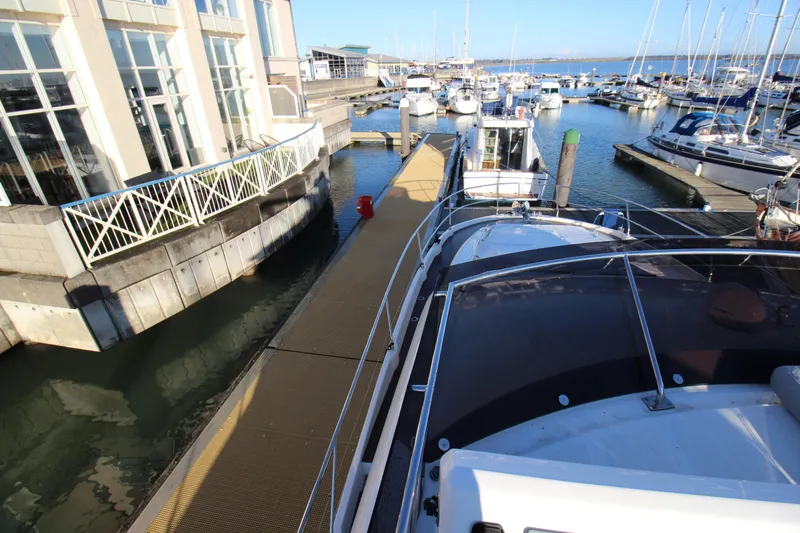  Yacht Photos Pics Marina view with 2024 Prestige 520 yacht docked alongside modern buildings.