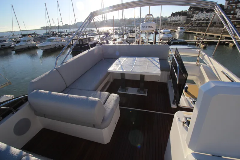  Yacht Photos Pics Luxurious 2024 Prestige 520 yacht deck with seating and table, docked at marina.