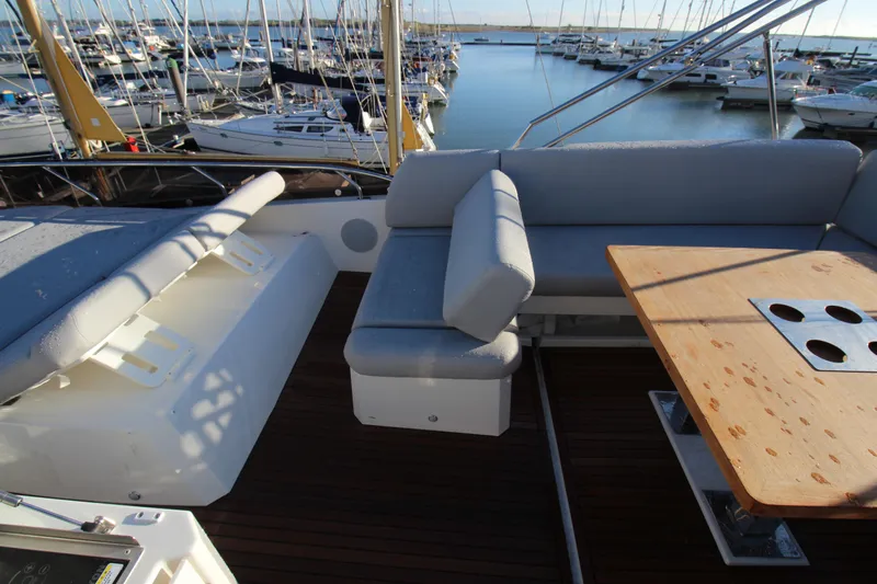  Yacht Photos Pics Luxurious 2024 Prestige 520 yacht deck with seating and wooden table in marina setting.