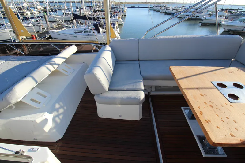  Yacht Photos Pics 2024 Prestige 520 yacht deck with seating and wooden table in marina.