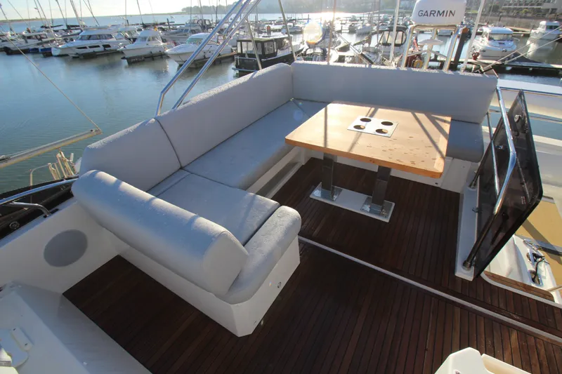  Yacht Photos Pics 2024 Prestige 520 yacht deck with cushioned seating and wooden table in marina.