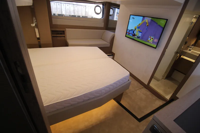  Yacht Photos Pics Luxurious 2024 Prestige 520 yacht bedroom with TV, modern decor, and cozy seating.