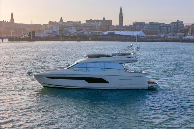  Yacht Photos Pics 2024 Prestige 520 yacht cruising near city skyline at sunset.