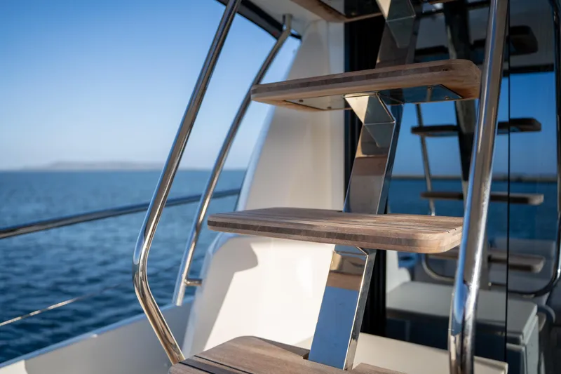  Yacht Photos Pics Stainless steel and wood staircase on 2024 Prestige 520 yacht, overlooking the ocean.