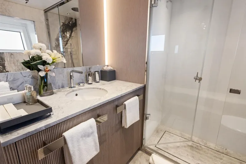 Contigo Yacht Photos Pics Luxurious bathroom in 2024 Benetti 40M Oasis yacht, featuring marble countertop and glass shower.