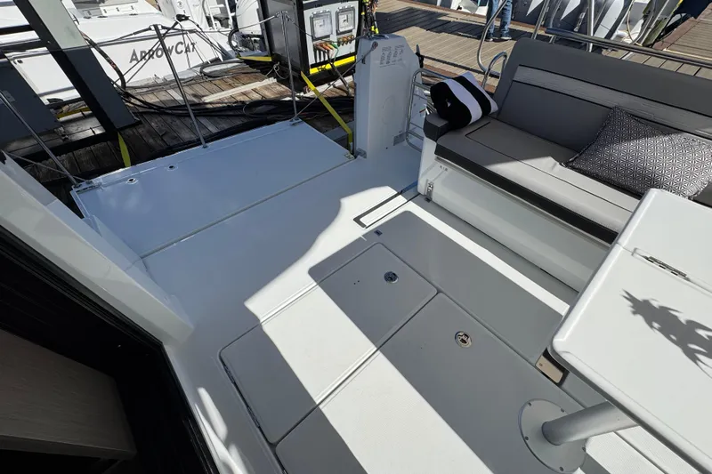  Yacht Photos Pics 2026 Jeanneau NC 1295 Coupe boat deck with seating and table, docked at marina.