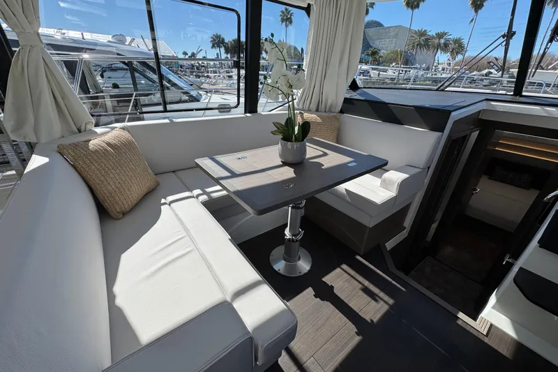  Yacht Photos Pics Interior of 2026 Jeanneau NC 1295 Coupe with elegant seating and table arrangement.