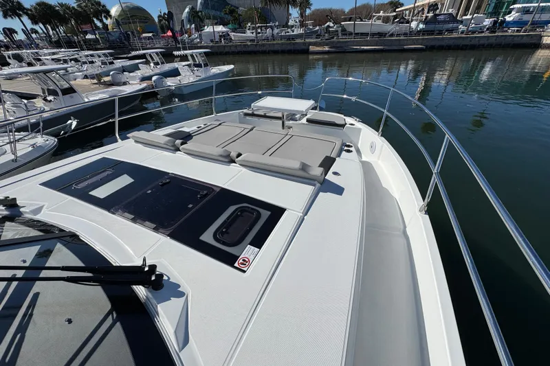  Yacht Photos Pics 2026 Jeanneau NC 1295 Coupe yacht with sunbathing area, docked at marina.