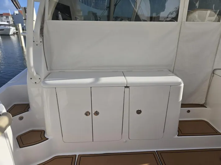 No Name Yacht Photos Pics 2019 Pursuit OS 385 Offshore boat interior with white cabinetry and teak flooring.