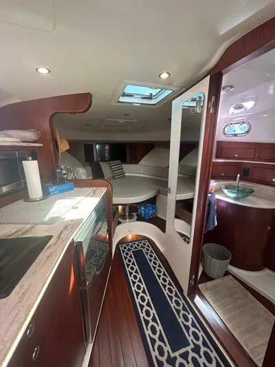 No Name Yacht Photos Pics 2019 Pursuit OS 385 Offshore interior with kitchen, seating, and bathroom. Luxurious wood finish.