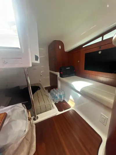 No Name Yacht Photos Pics 2019 Pursuit OS 385 Offshore cabin interior with seating, wooden flooring, and storage.