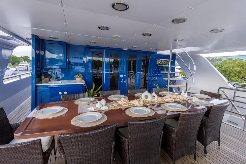 Ionian Princess Yacht Photos Pics Luxurious yacht dining area with wicker chairs, elegant table setting, and blue cabinetry, Christensen 2005 model.