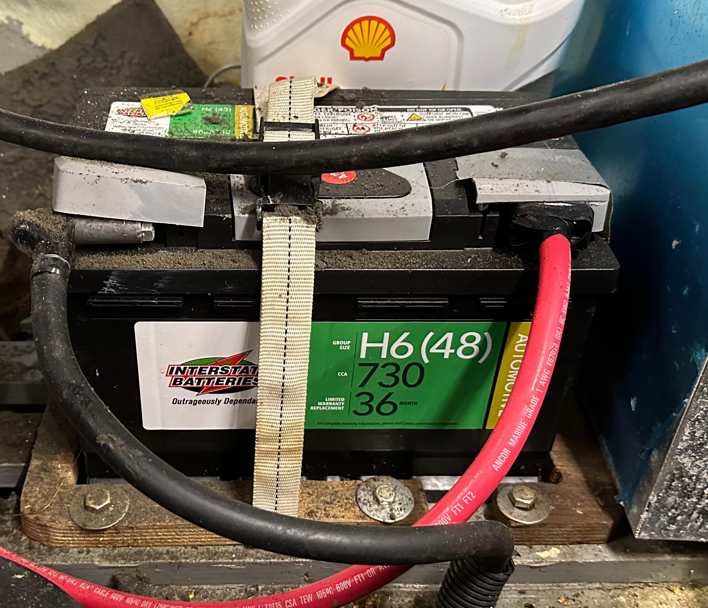 Car battery with cables, Interstate Batteries H6(48) 730 CCA, Shell oil container in background.