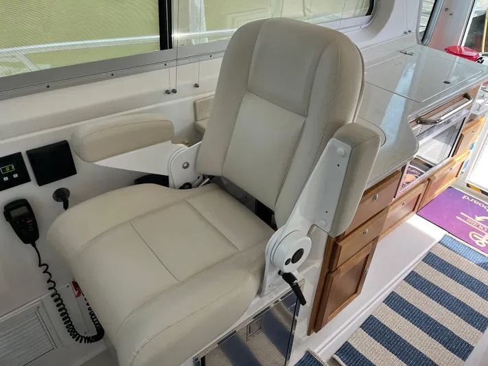  Yacht Photos Pics 2016 Back Cove 34 Express helm seat with white upholstery and adjacent control panel.