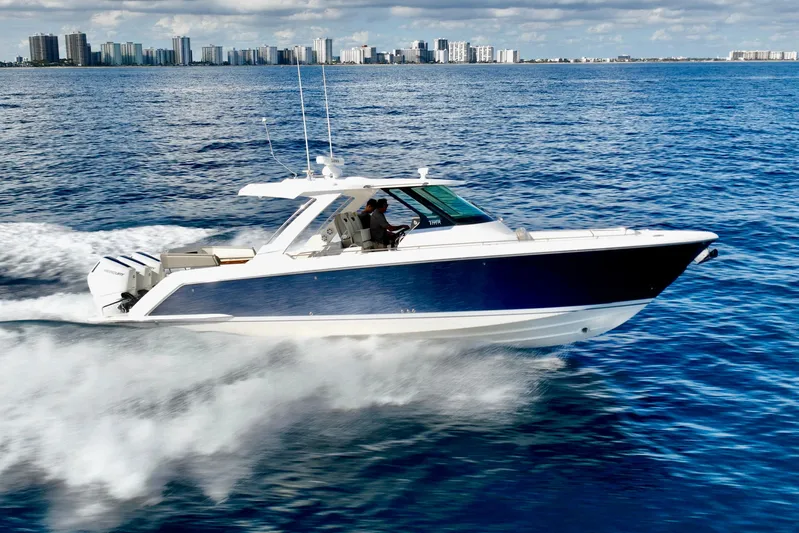 S.y. Royale Yacht Photos Pics 2023 Tiara Sport 38 LS cruising on ocean with city skyline in background.