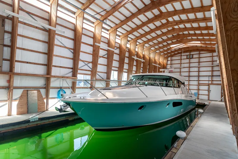 Noor Yacht Photos Pics 2023 Tiara Yachts C44 Coupe in a covered dock, showcasing sleek design and vibrant hull.