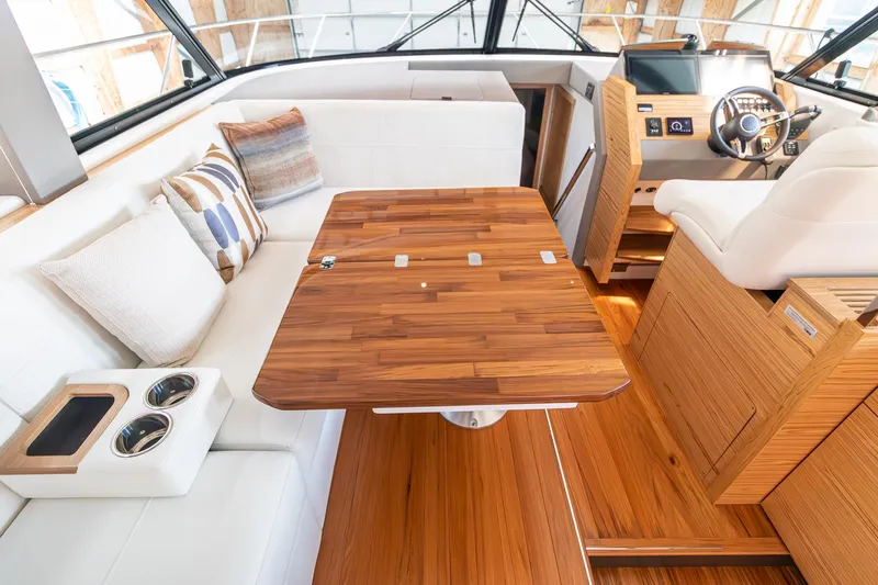 Noor Yacht Photos Pics 2023 Tiara Yachts C44 Coupe interior with wooden table, white seating, and helm station.