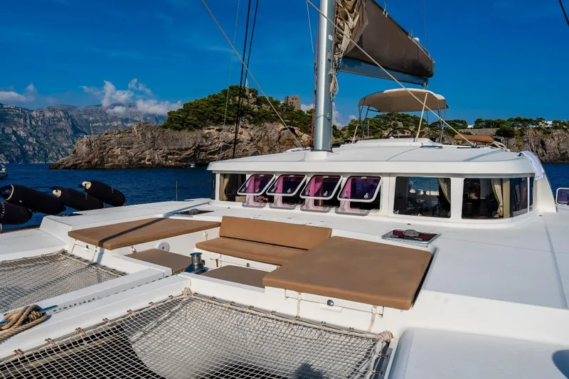  Yacht Photos Pics 2011 Lagoon 500 yacht with sunbathing area, sailing near rocky coastline.